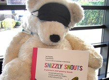 Blindfolded white bear, presenting the Snizzly Snouts book
