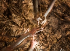 Sepiakleurige foto van handen die naar elkaar reiken en in het zand woelen (copyright Hilde Braet en Benny De Grove)