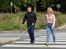 Blinde persoon met witte stok en mobiliteitsinstructeur die smartphone vasthoudt