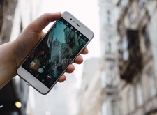 Iemand houdt een smartphone voor zich en maakt daarmee het wazige straatbeeld scherp.