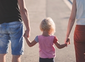 Ouders op wandel met kindje, hand in hand met het kind in het midden